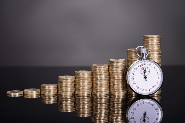 Stacks of coins increasing in height next to a stopwatch symbolizing fast financial gain and compliance risk