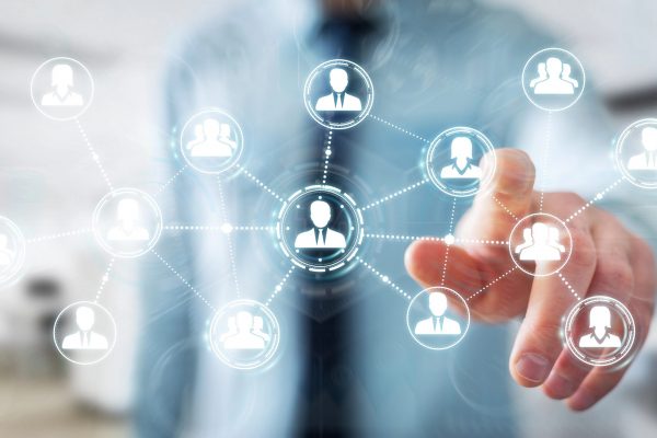 Business professional selecting connected user icons on digital network interface representing structured ITAD network coordination